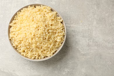 Photo of Delicious bulgur in bowl on gray table, top view. Space for text