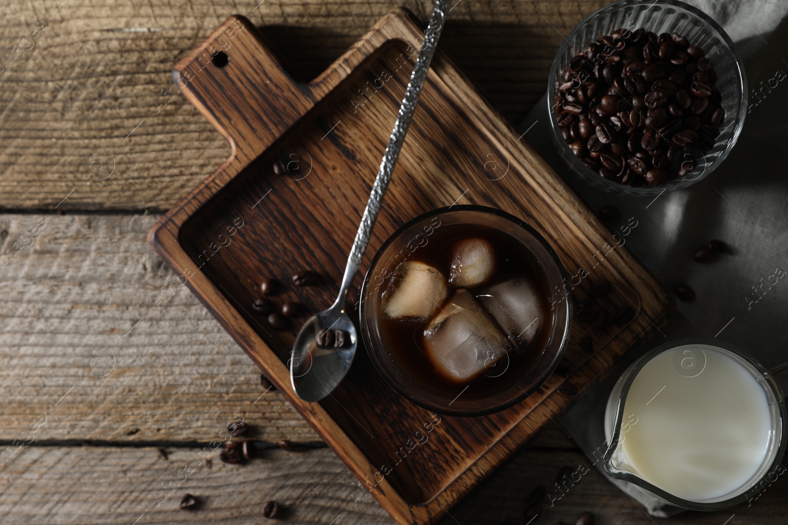 Photo of Delicious iced coffee, milk and beans on wooden table, flat lay