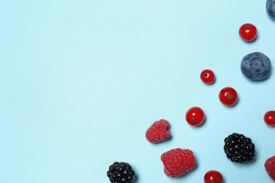 Photo of Different fresh berries on light blue background, flat lay. Space for text