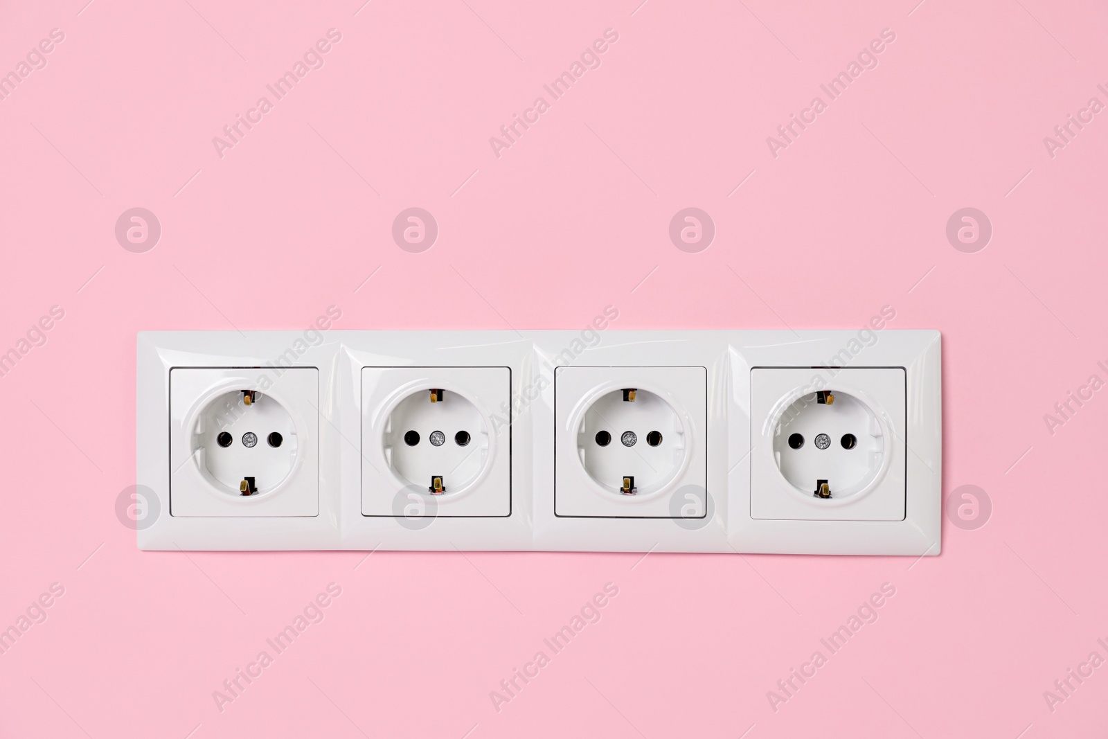 Photo of Power sockets on pink wall. Electrical supply