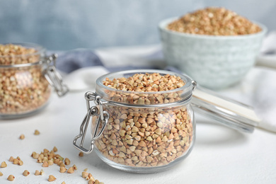 Jar with green buckwheat on white table