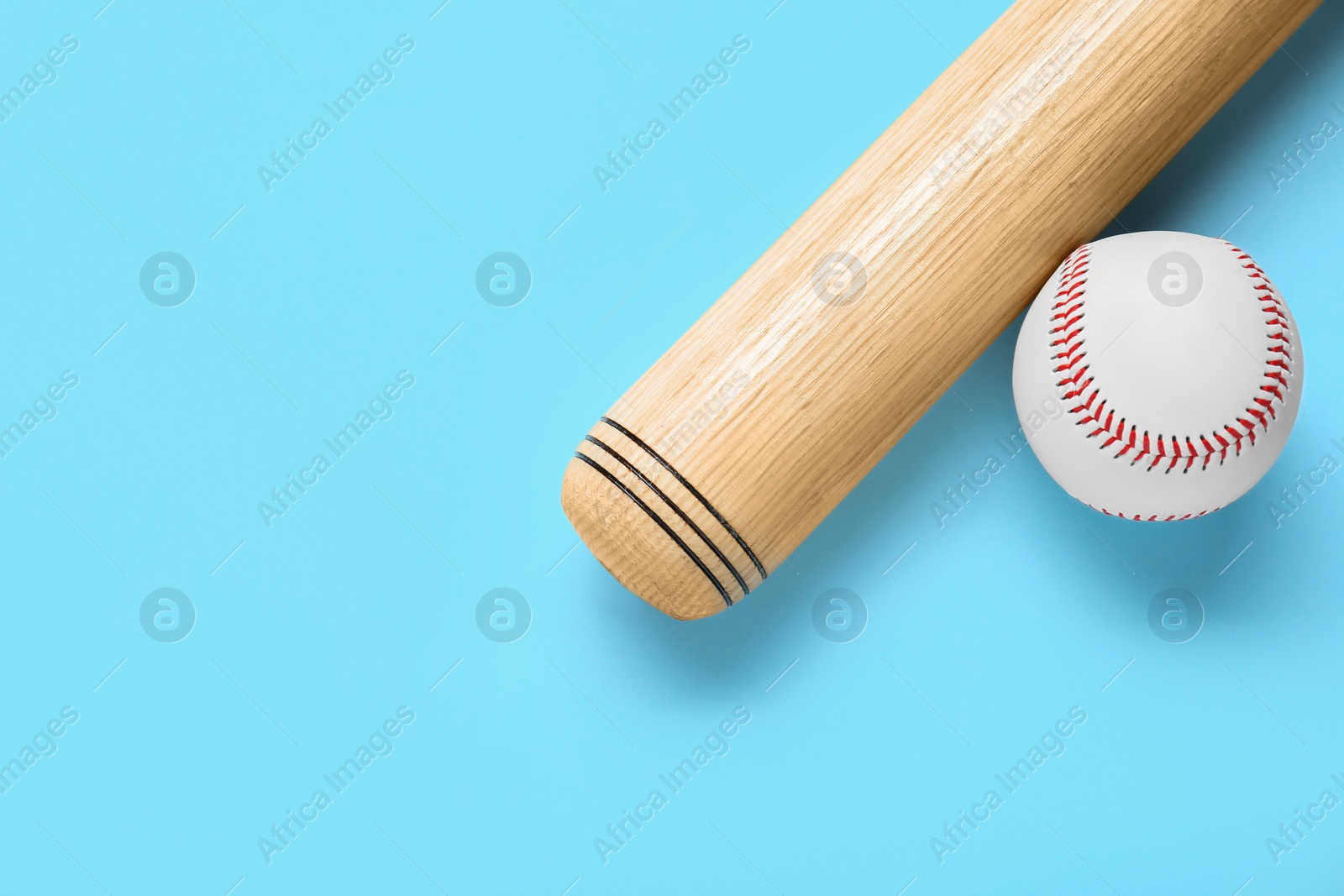 Photo of Wooden baseball bat and ball on light blue background, flat lay. Space for text