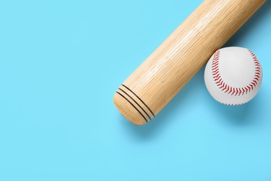 Photo of Wooden baseball bat and ball on light blue background, flat lay. Space for text