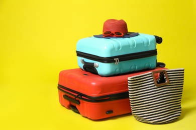 Stylish suitcases and beach accessories on yellow background