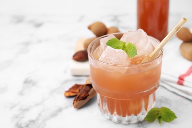 Photo of Freshly made tamarind juice with mint on white marble table, closeup. Space for text