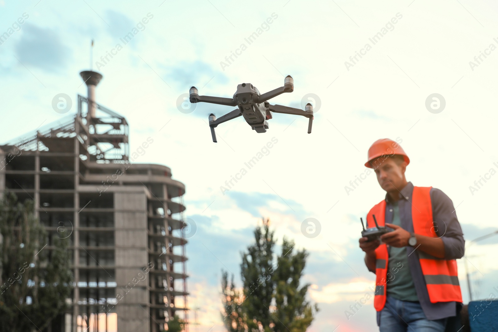 Photo of Builder operating drone with remote control at construction site, focus on quadcopter. Aerial survey