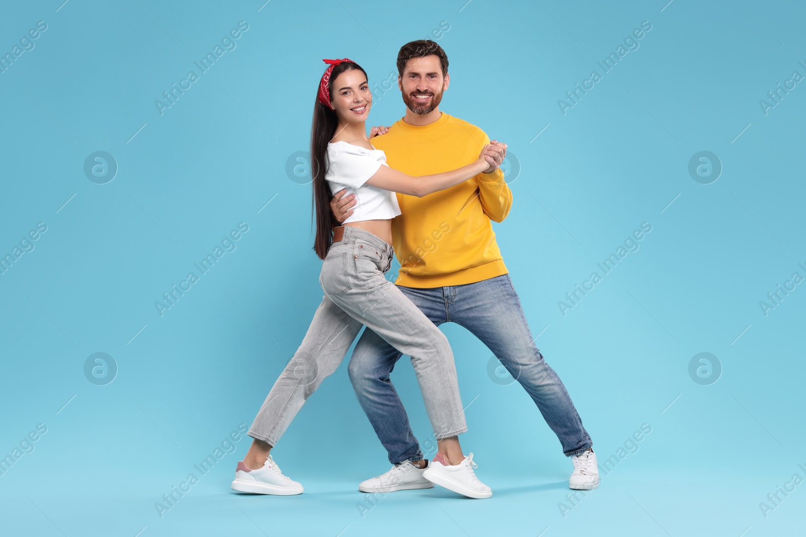 Photo of Happy couple dancing together on light blue background