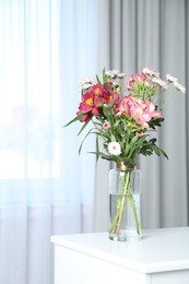 Vase with beautiful flowers on table near window indoors. Stylish element of interior design