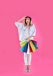 Photo of Beautiful young woman with shopping bags on color background