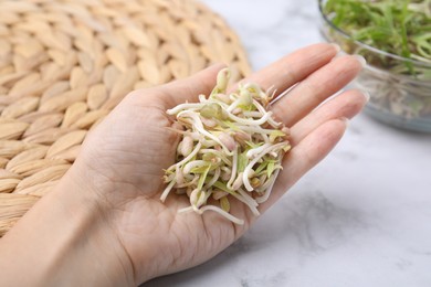 Photo of Woman holding mung bean sprouts at white marble table, closeup