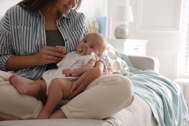 Photo of Happy mother holding her cute little baby with pacifier at home