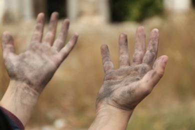 Photo of Poor homeless child begging for help outdoors, closeup