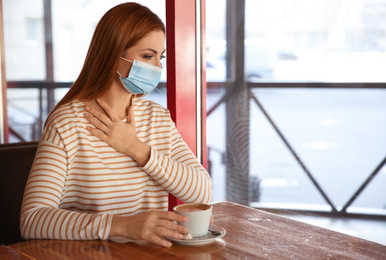 Woman with medical mask in cafe. Virus protection