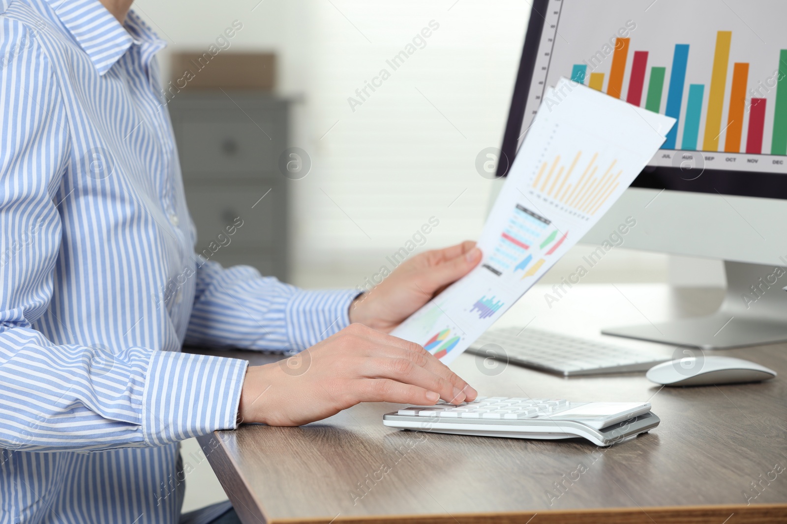 Photo of Professional accountant using calculator at wooden desk in office, closeup