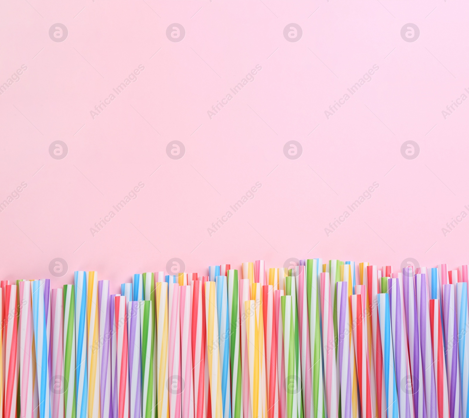 Photo of Heap of colorful plastic drinking straws on pink background, flat lay. Space for text