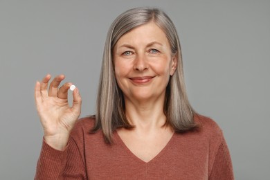 Photo of Senior woman with pill on grey background