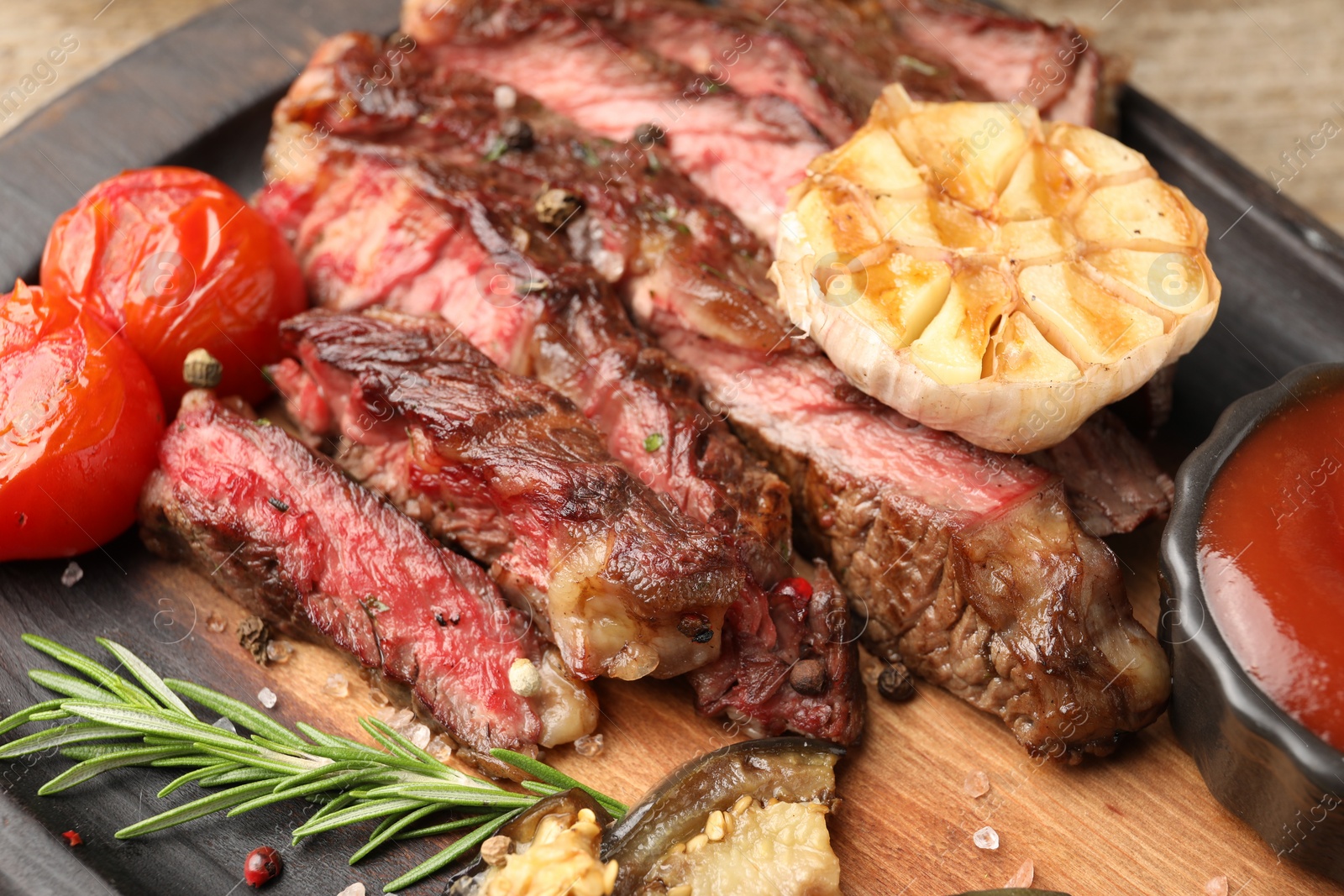 Photo of Delicious grilled beef steak with vegetables and spices on table, closeup