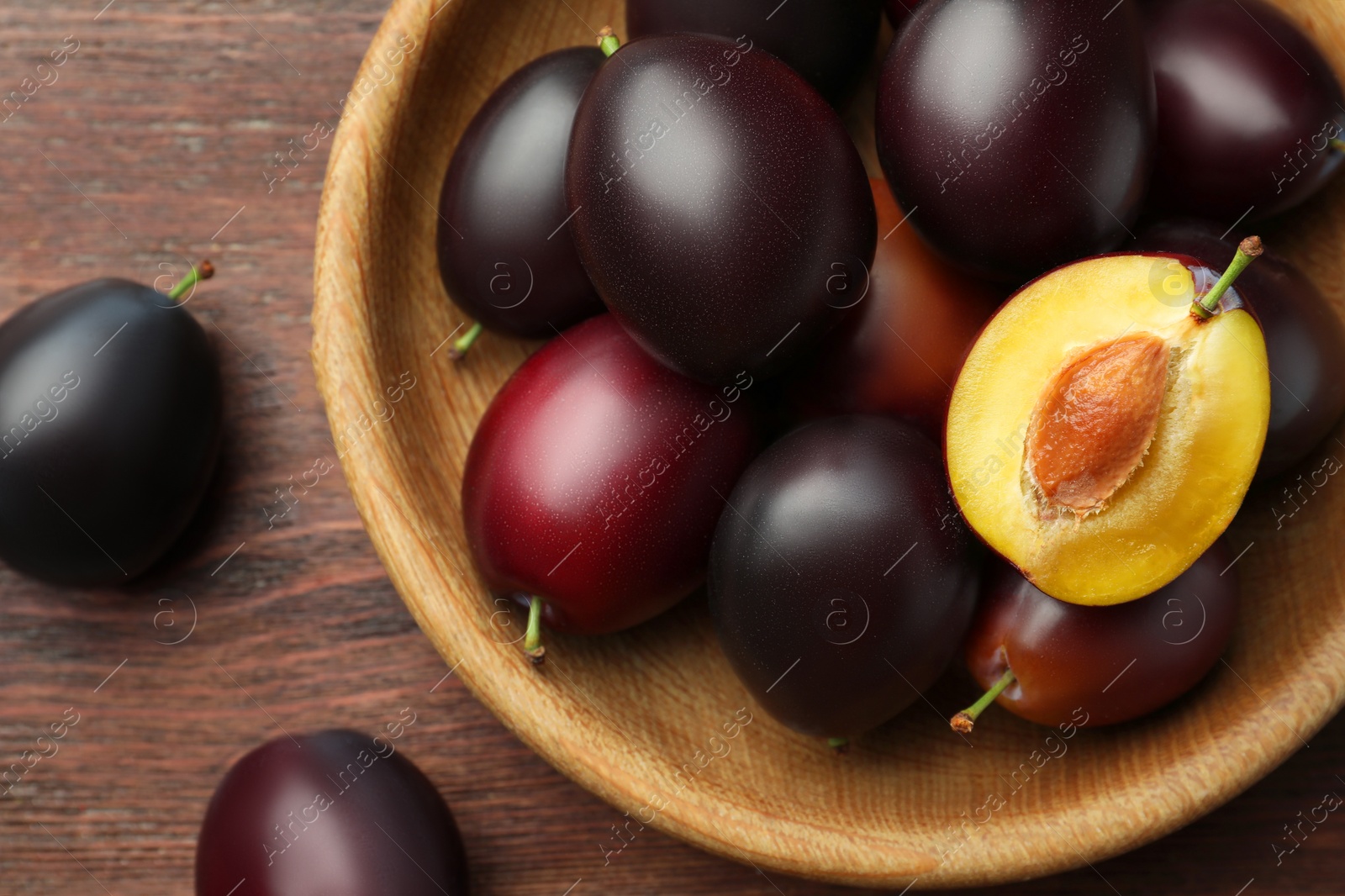 Photo of Tasty ripe plums on wooden table, flat lay