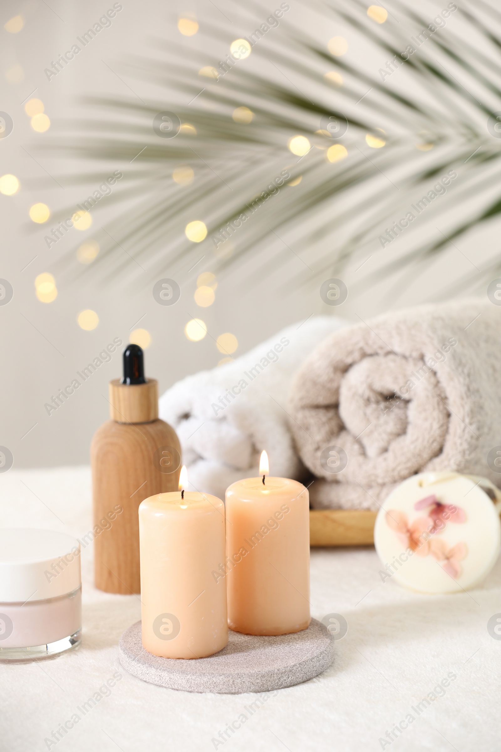 Photo of Spa composition. Burning candles and personal care products on soft white surface