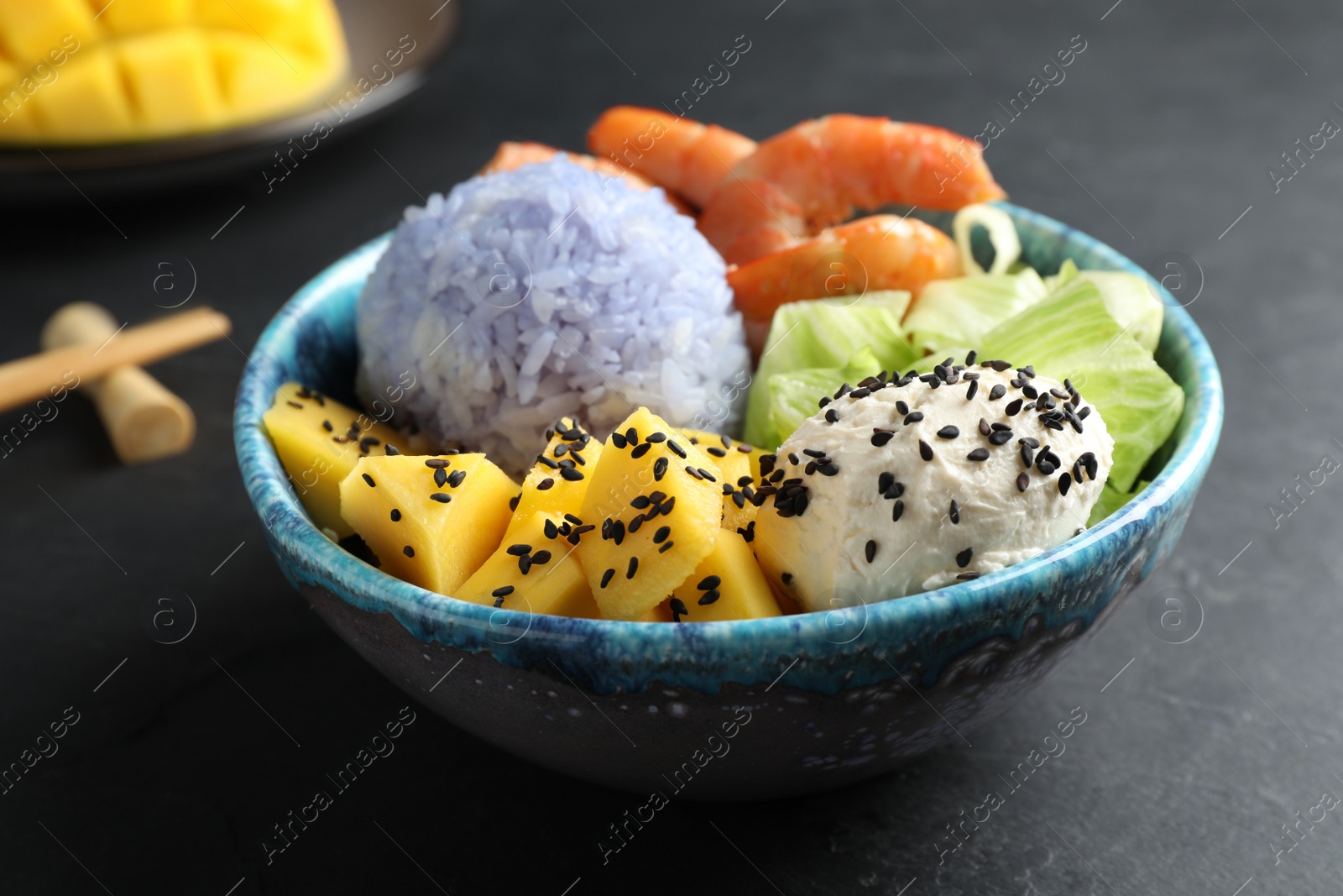 Photo of Delicious poke bowl served on black table, closeup