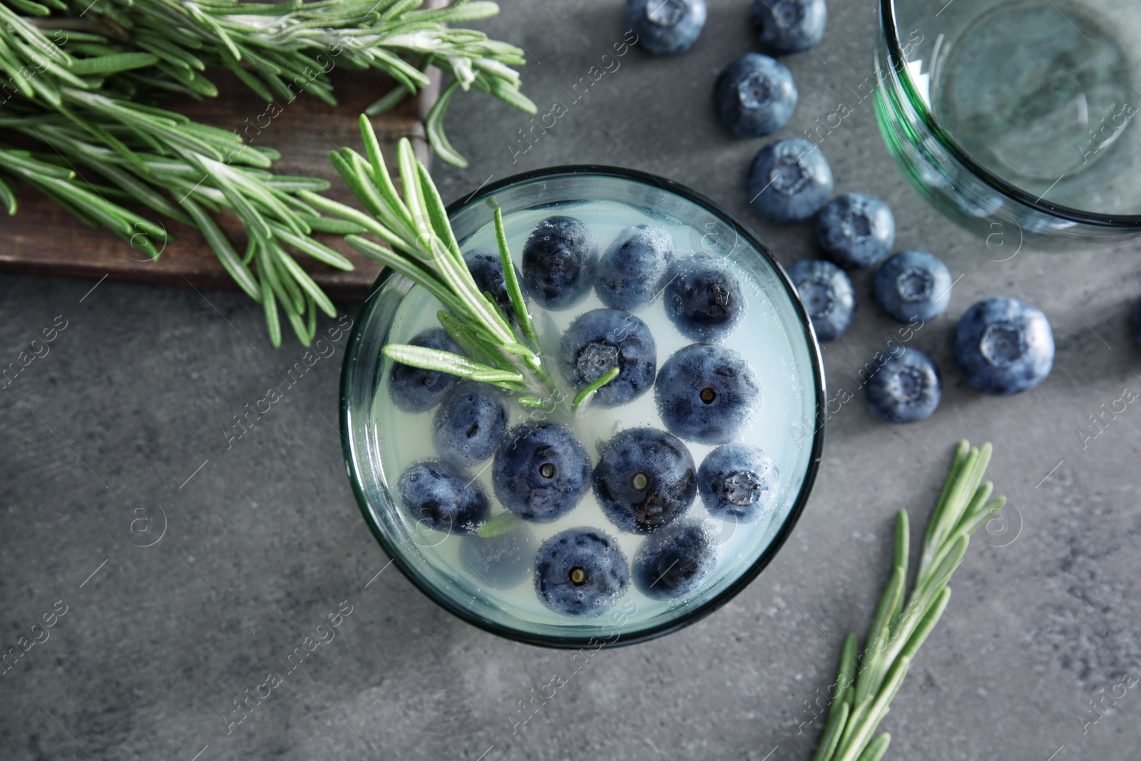 Photo of Flat lay composition with glass of blueberry and rosemary cocktail on gray table