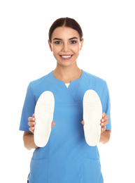 Female orthopedist showing insoles on white background