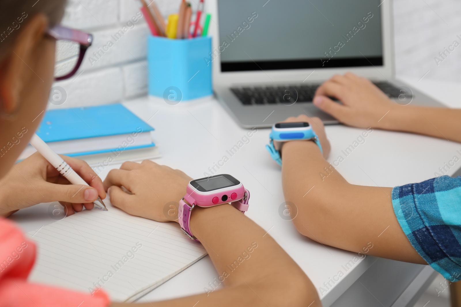 Photo of Children with stylish smart watches at white table, closeup