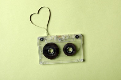 Photo of Music cassette and heart made with tape on green background, top view. Listening love song