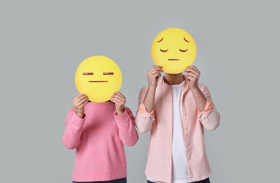 Photo of People covering faces with sad emoticons on grey background