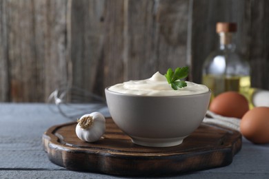 Photo of Tasty mayonnaise in bowl and ingredients on light grey wooden table, space copy text