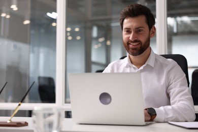 Portrait of smiling man working with laptop in office, space for text. Lawyer, businessman, accountant or manager