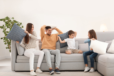 Photo of Happy family having pillow fight in living room