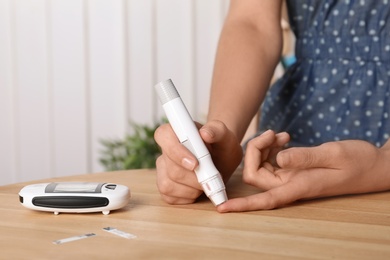 Woman using lancet pen at table. Diabetes test