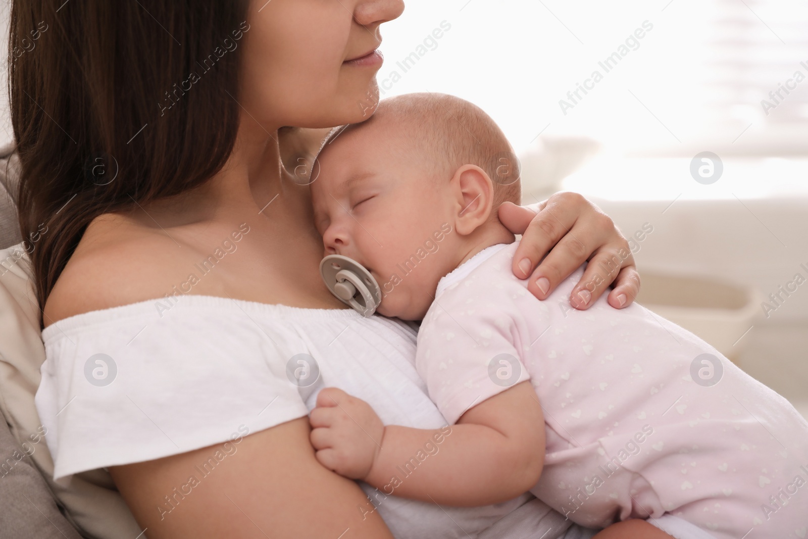 Photo of Happy young mother with her sleeping baby on chair  at home, closeup