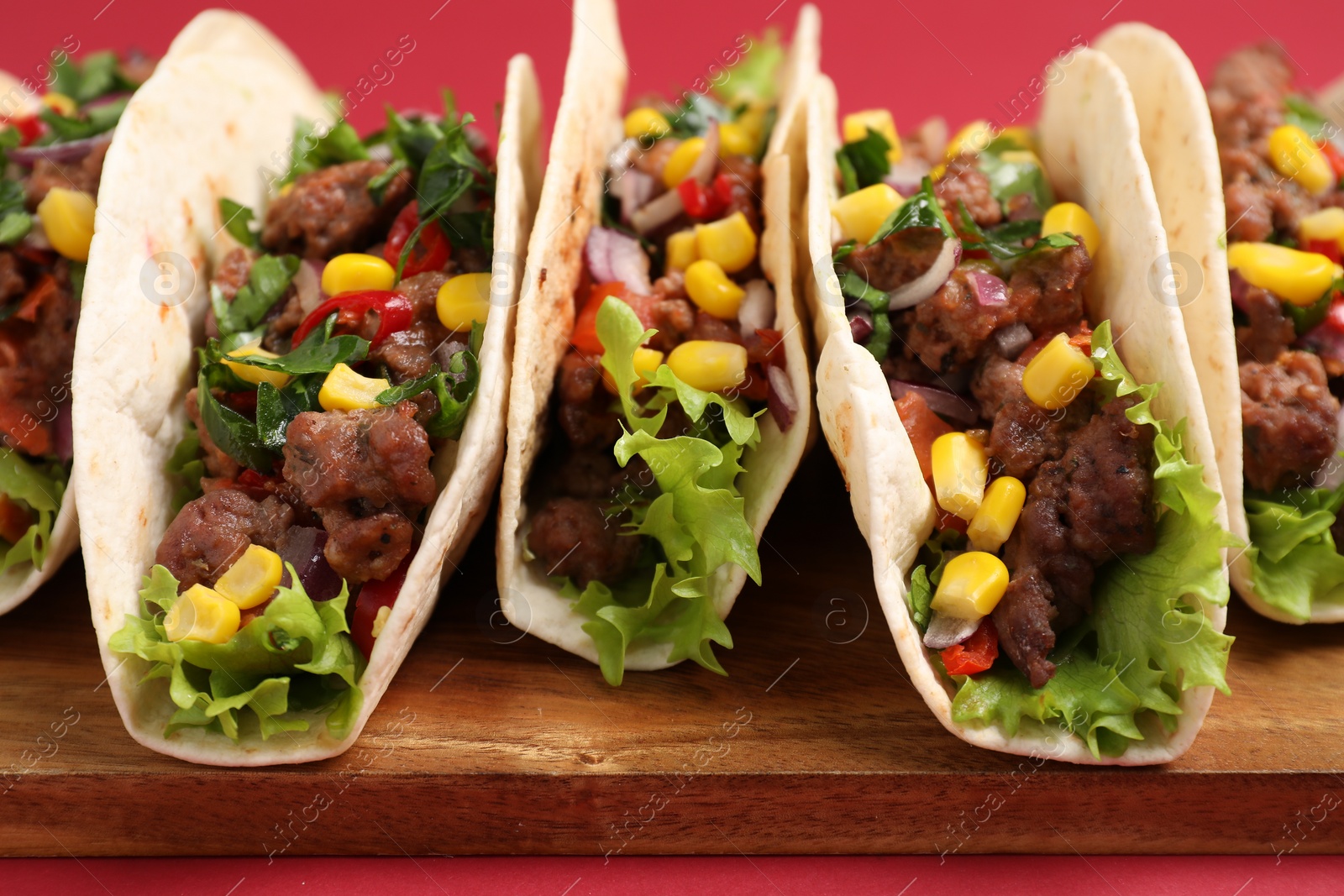 Photo of Delicious tacos with meat and vegetables on table, closeup