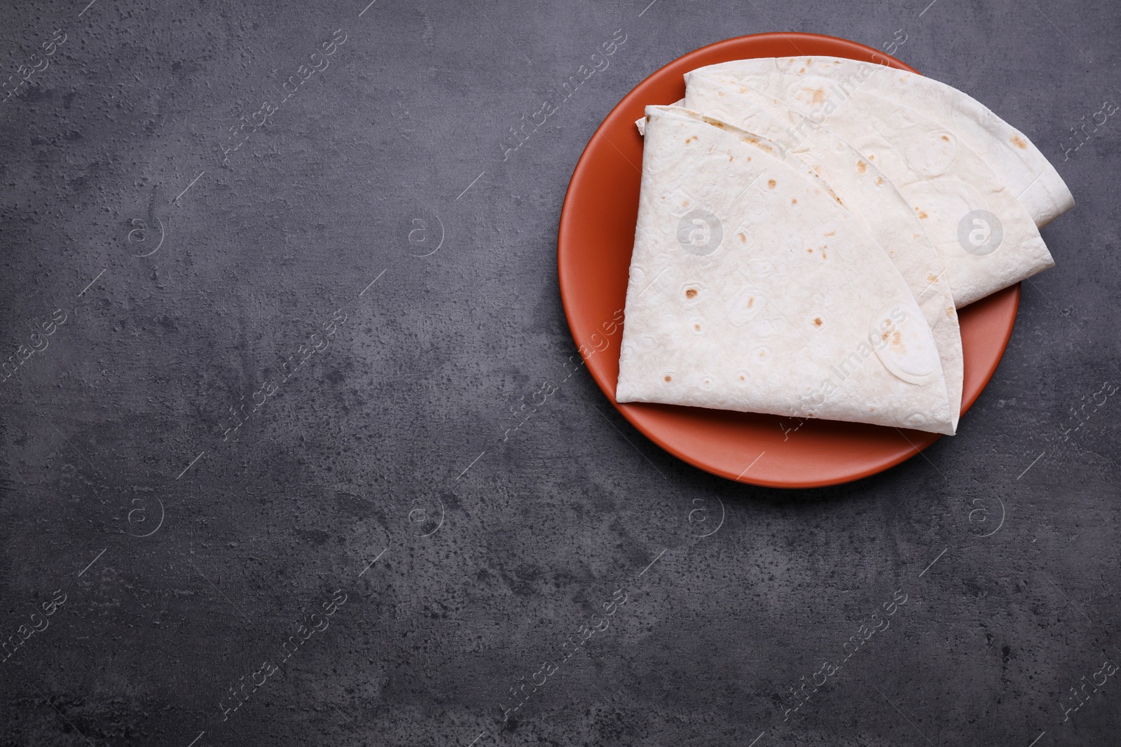 Photo of Delicious folded Armenian lavash on dark table, top view. Space for text