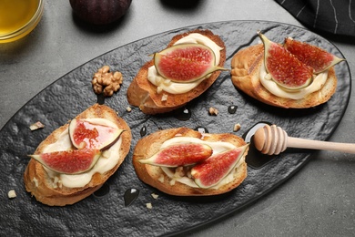 Photo of Bruschettas with ripe figs and cream cheese served on grey table, top view