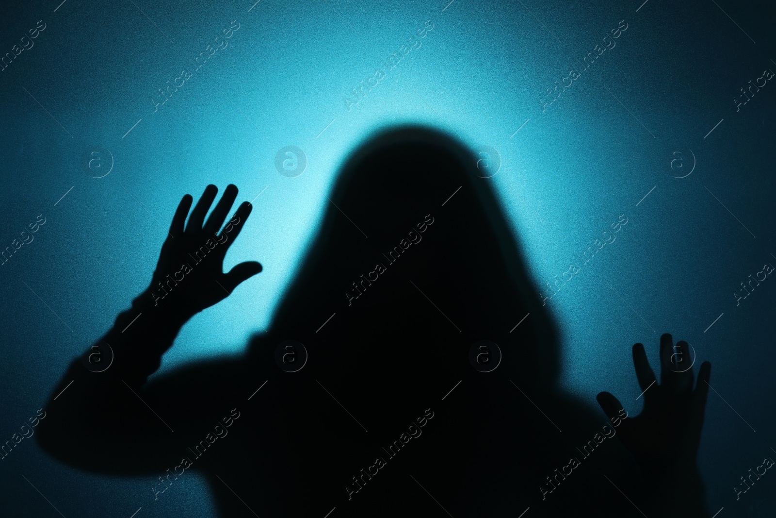 Photo of Silhouette of ghost behind glass against blue background