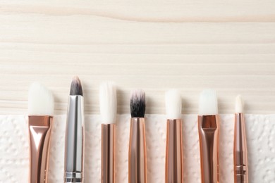 Photo of Set of different makeup brushes drying after cleaning on white wooden table, flat lay. Space for text