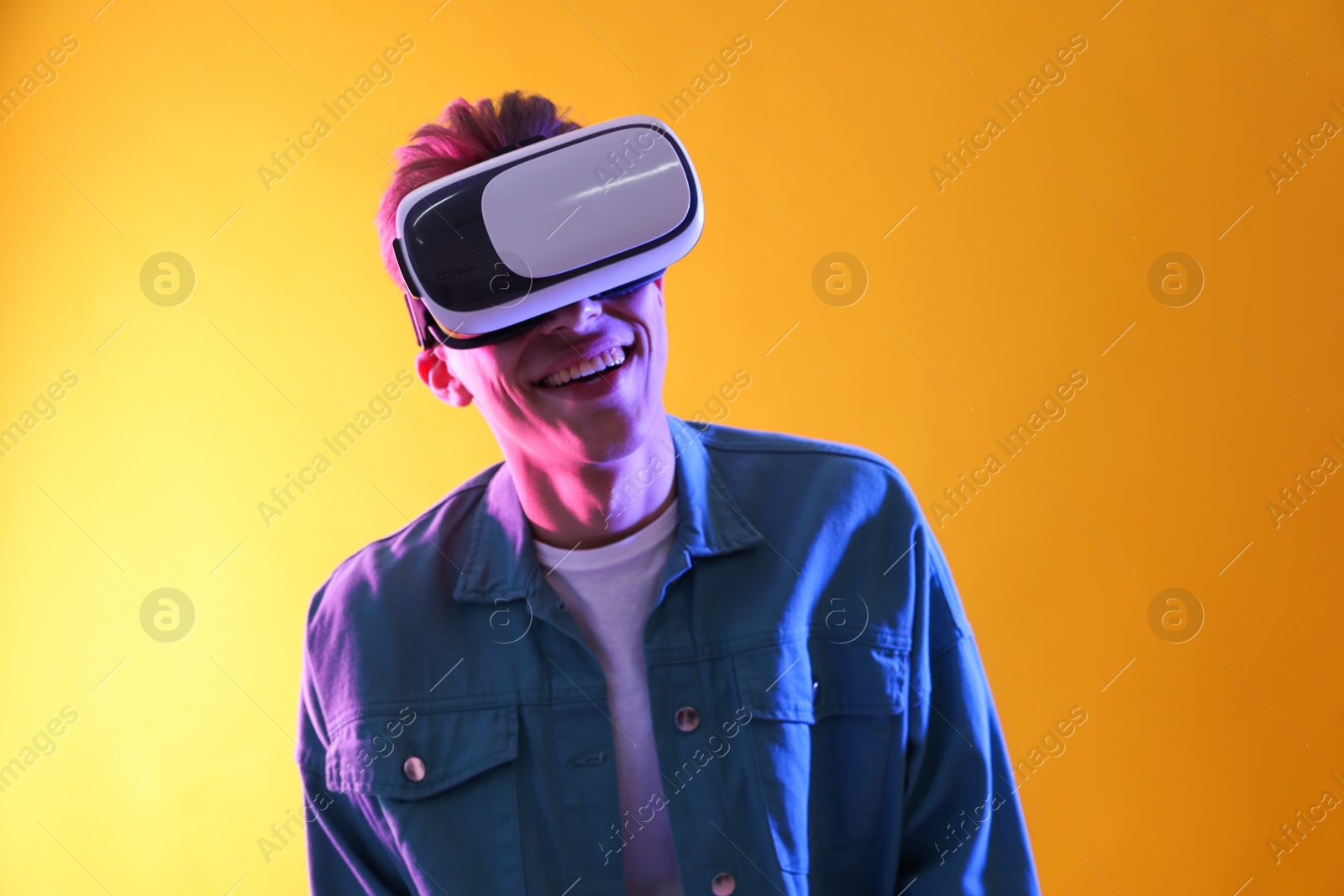 Photo of Young man with virtual reality headset on yellow background