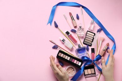 Photo of Woman with different makeup products and beautiful spring flowers on pink background, top view. Space for text