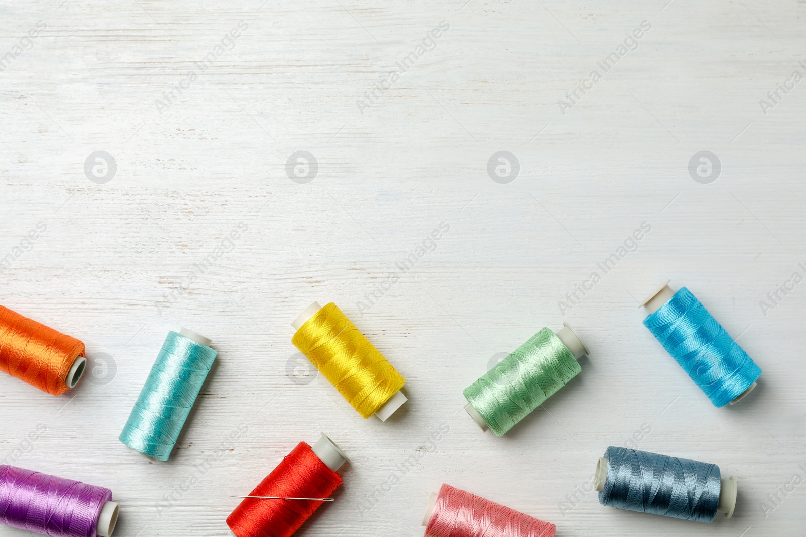 Photo of Color sewing threads on wooden background, top view