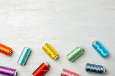 Color sewing threads on wooden background, top view