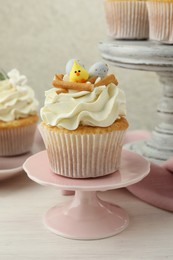 Tasty Easter cupcakes with vanilla cream on light wooden table