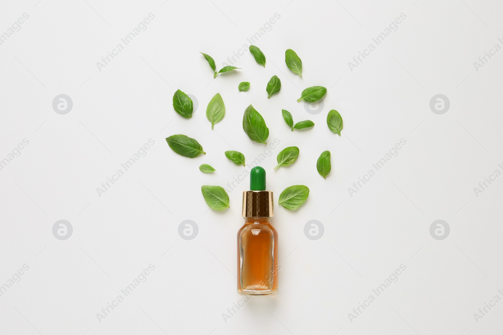 Photo of Bottle of essential basil oil and fresh leaves on white background, flat lay