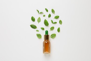 Photo of Bottle of essential basil oil and fresh leaves on white background, flat lay