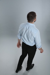 Man in formal clothes on grey background, back view