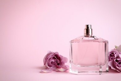 Photo of Bottle of perfume and beautiful roses on pink background. Space for text