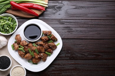 Photo of Tasty soy sauce, roasted meat and ingredients on wooden table, flat lay. Space for text