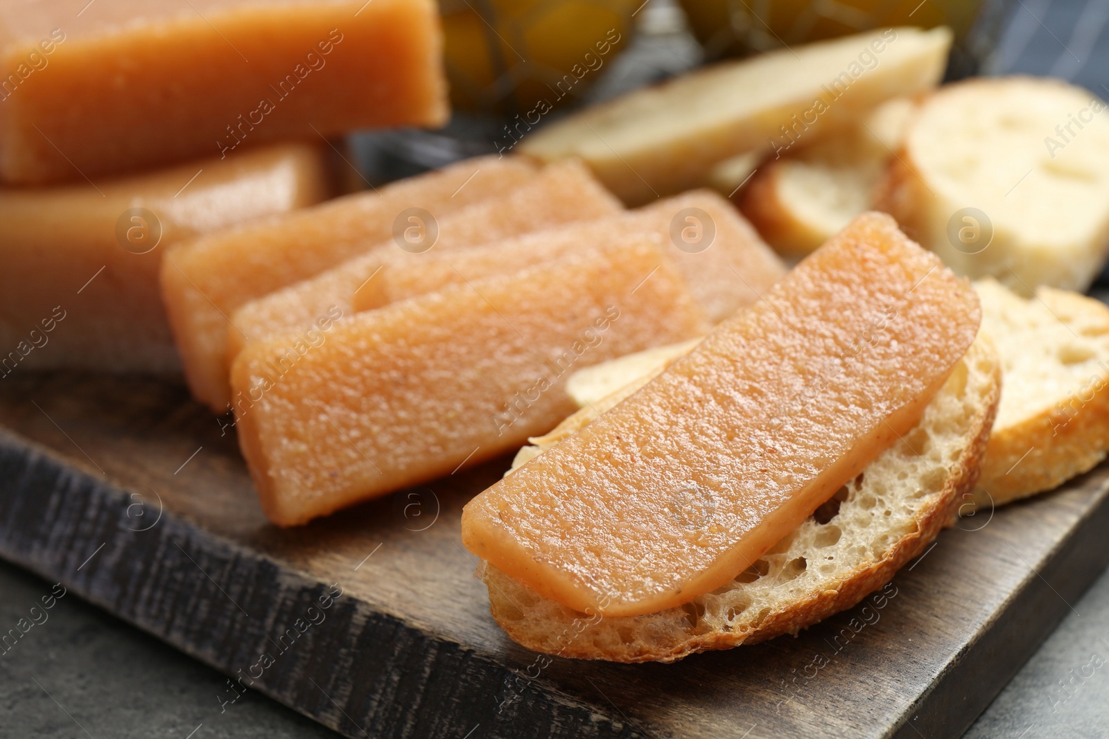 Photo of Tasty sweet quince paste and bread on grey table, closeup